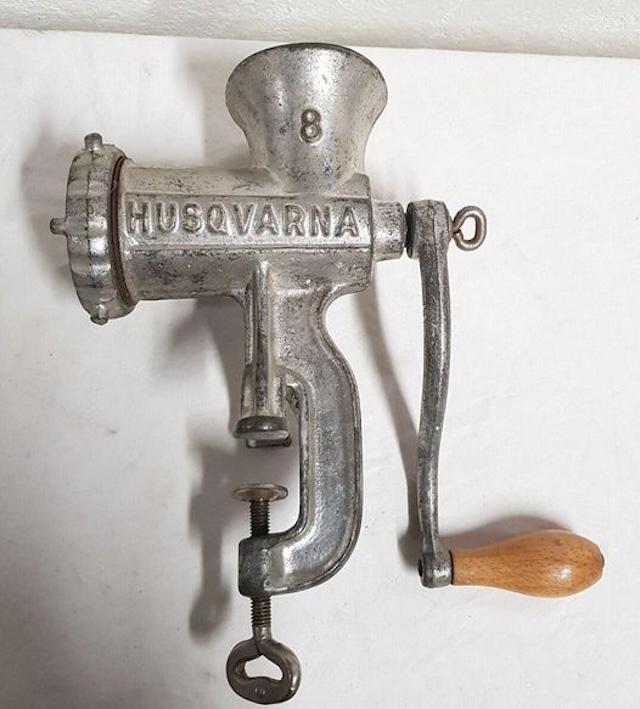 An antique meat mincer from the renowned brand Husqvarna, showcasing the sturdy construction and timeless design that made it a kitchen essential in the past.